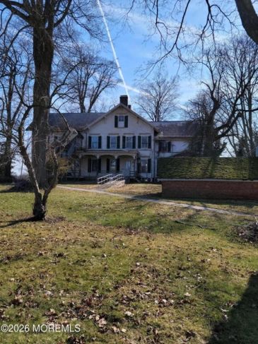 Brick colonial house with white trim and manicured lawn